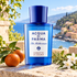 Acqua di Parma Chinotto di Liguria on sunlit stone beside citrus, rosemary, and white flowers, overlooking a pastel Ligurian village and blue sea.