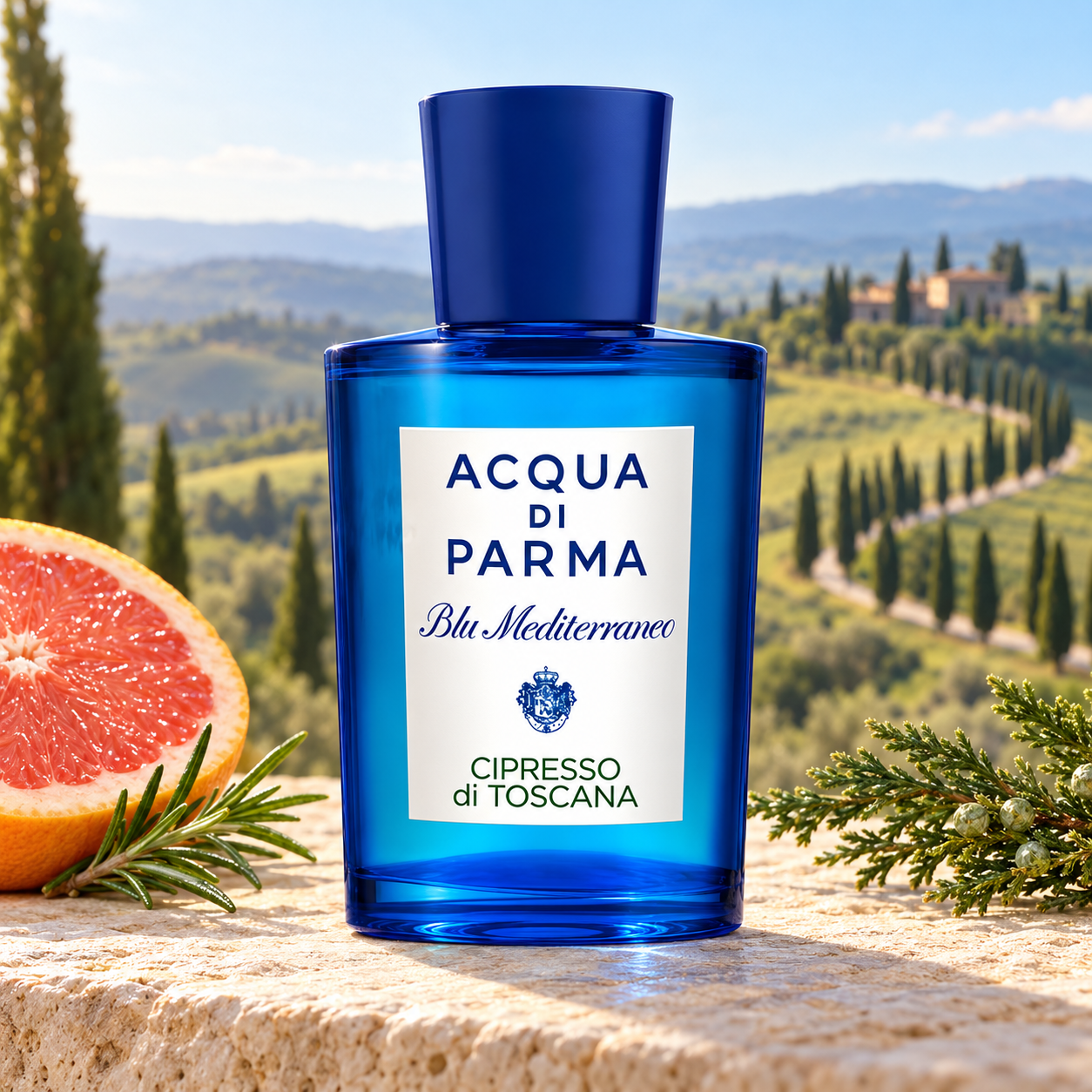 Acqua di Parma Cipresso di Toscana’s blue bottle on sunlit limestone beside grapefruit, rosemary, and cypress, overlooking softly blurred Tuscan hills.