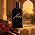 Akro East black bottle on sandstone beside raspberries, oud wood and brown leather, with a softly blurred archway in golden evening light.