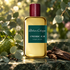 Atelier Cologne Emeraude Agar perfume beside eucalyptus, whole bergamot and dark wood on green stone in dappled sunlight.