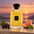 Atelier des Ors Aube Rubis on a stone ledge beside blackcurrants, grapefruit, and patchouli leaves against a golden sunrise.