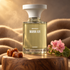 BORNTOSTANDOUT WARM AIR perfume bottle on a wooden pedestal with caramel pieces, pink geranium flowers, and soft camel fabric in golden light.