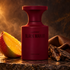 BORNTOSTANDOUT Black Mango beside a large mango cheek, oud wood, and brown leather on dark stone in smoky amber light.