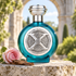 Boadicea the Victorious Decade bottle with a pink rose and wood on a sunlit stone plinth before a garden arch.