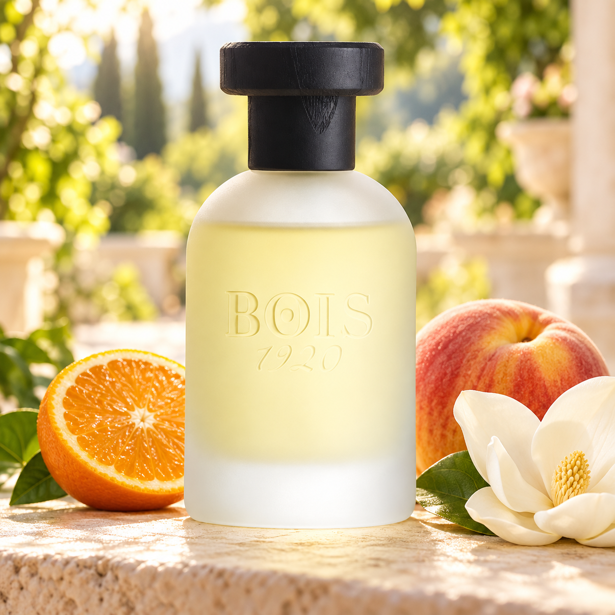 Bois 1920 Classic Paradise frosted bottle beside an orange half, ripe peach, and white magnolia on sunlit stone in a softly blurred garden.
