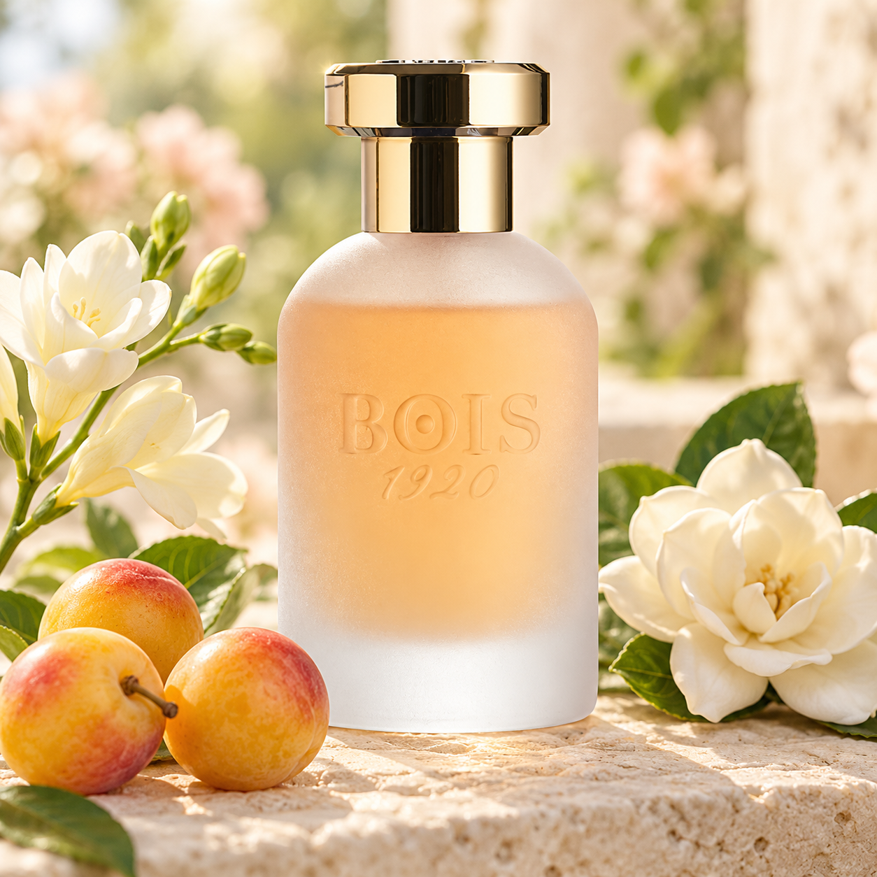 Bois 1920 Come L’Amore’s frosted bottle on sunlit limestone beside golden Mirabelle plums, white freesias, and a gardenia.