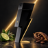Carolina Herrera Bad Boy’s black-and-gold lightning-bolt bottle beside bergamot, clary sage, and cacao against a dark background with diagonal golden light.