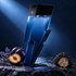 Carolina Herrera Bad Boy Cobalt’s blue lightning-bolt bottle on dark slate beside lavender, black plums, and sliced truffle under cool blue light.