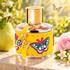 Carolina Herrera CH Beauties beside a pear, pink peony, and jasmine on sunlit stone, with a butterfly above a softly blurred garden.