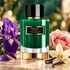 Carolina Herrera Emerald Musk perfume with purple iris, pink rose and vanilla orchid on pale stone in warm light.
