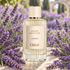 Chloé Lavanda framed by abundant purple lavender on a sunlit limestone table, with a softly blurred lavender garden behind it.
