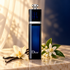 Dior Addict Eau de Parfum beside a vanilla orchid, vanilla pods, and orange blossoms on ivory stone in warm, soft light.
