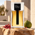Dior Homme 2020 bottle with pink pepper and a whole bergamot on pale cedar against sunlit stone architecture.
