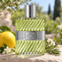 Dior Eau Sauvage bottle beside a whole lemon, rosemary and white jasmine on sunlit garden stone.