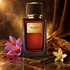 Dolce&Gabbana Velvet Zafferano stands on dark marble beside purple saffron crocuses, tobacco leaves, and vanilla pods with an orchid in warm amber light.