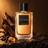 Elie Saab Essence No. 4 Oud bottle on dark stone with agarwood, black peppercorns and resin in warm amber light.