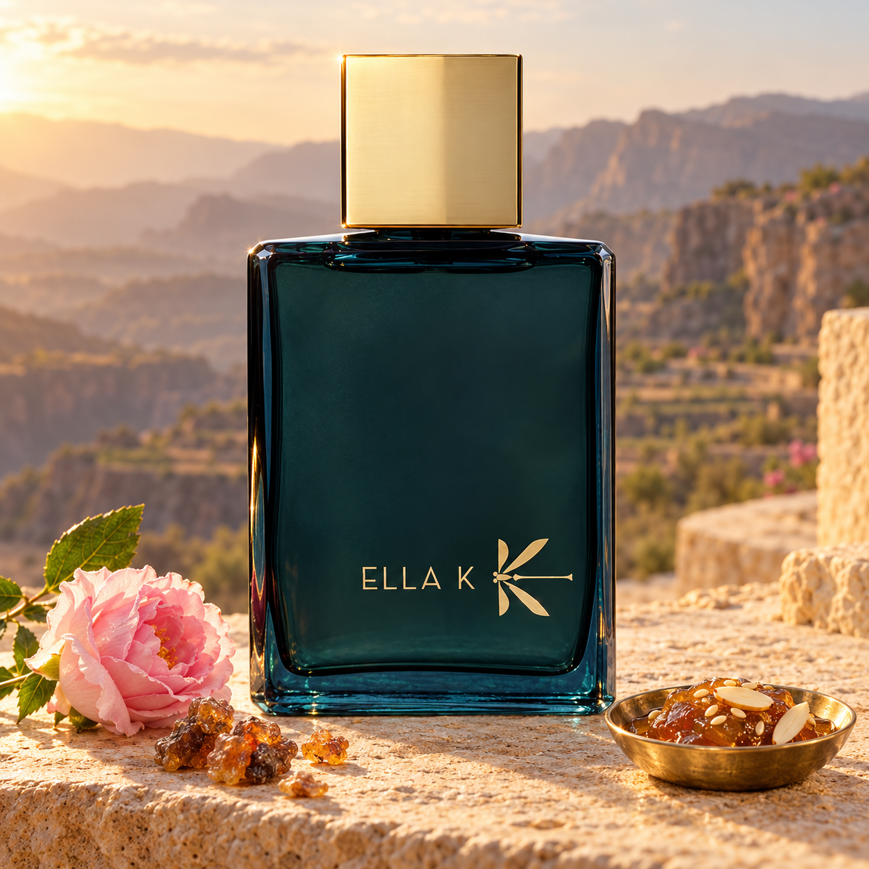 Ella K Myrrh K with a pink rose, myrrh resin, and Omani halwa on limestone overlooking sunlit mountain terraces.