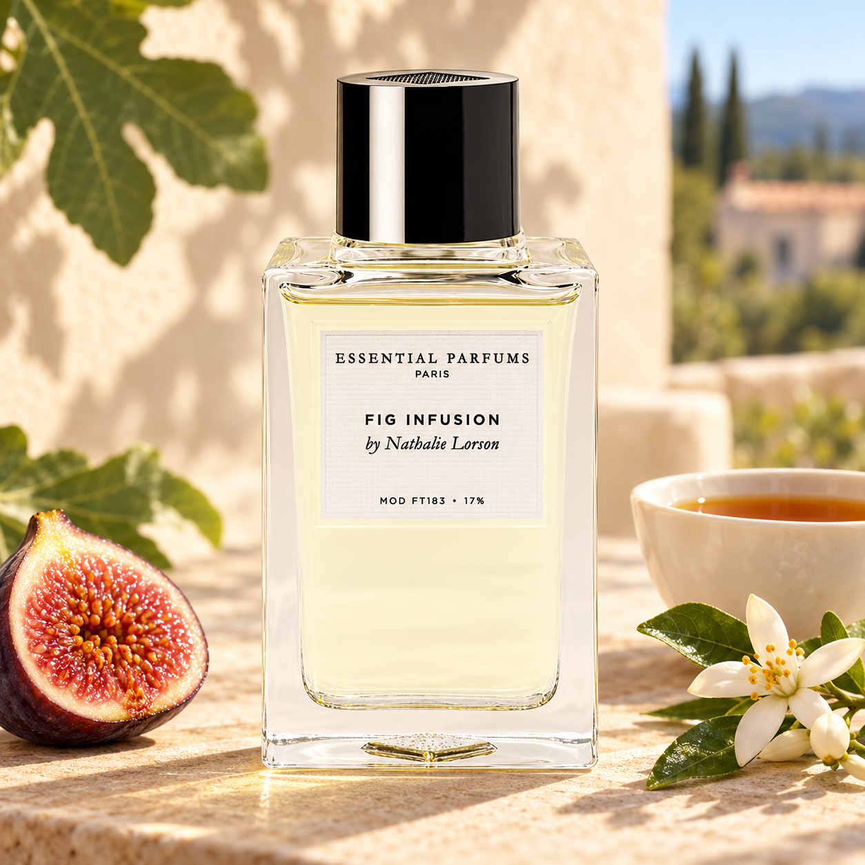Essential Parfums Fig Infusion on a sunlit stone terrace with a cut fig, a cup of black tea and white orange blossoms.