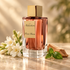 Franck Boclet Addiction beside white tuberose flowers, fresh basil, and sandalwood on pale stone in warm golden light.