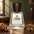 Frapin Attendre & Espérer on a wooden desk beside walnut, vetiver roots, and cardamom, with a leather-bound book in soft window light.