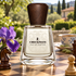 Frapin Checkmate on a wooden chessboard with chess pieces, purple iris, and cardamom tea in a sunlit garden.