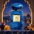 Armani Privé Bleu Lazuli on blue stone with plum, honeycomb, and tobacco, framed by a golden Indian-style arch overlooking water at twilight.