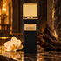 Gritti Oud Reale black and gold perfume bottle with an orchid and dark wood on polished stone in warm golden light.