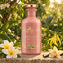 Pink Gucci A Chant for the Nymph bottle beside frangipani, ylang-ylang, and a vanilla orchid in a sunlit tropical garden.