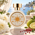 HFC SunMusk perfume bottle with golden sun artwork, white dahlias, bergamot, and pink peppercorns on a sunlit terrace overlooking the Mediterranean