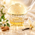 House of Sillage Benevolence beside orange blossoms, almonds, and a vanilla orchid on ivory stone, surrounded by soft silk and golden light.