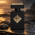 Initio Magnetic Blend 1 on dark coastal stone beside smooth pebbles, with warm sunset light and a misty ocean background.