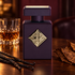 Initio Side Effect bottle with vanilla pods, tobacco leaves, and a glass of rum on dark wood in warm amber lighting.
