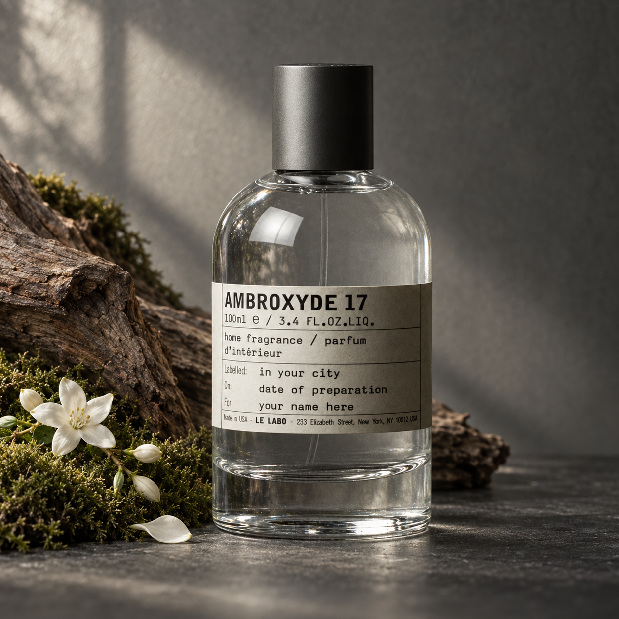 Le Labo AMBROXYDE 17 home fragrance bottle beside weathered wood, green moss, and white jasmine flowers in soft directional light.