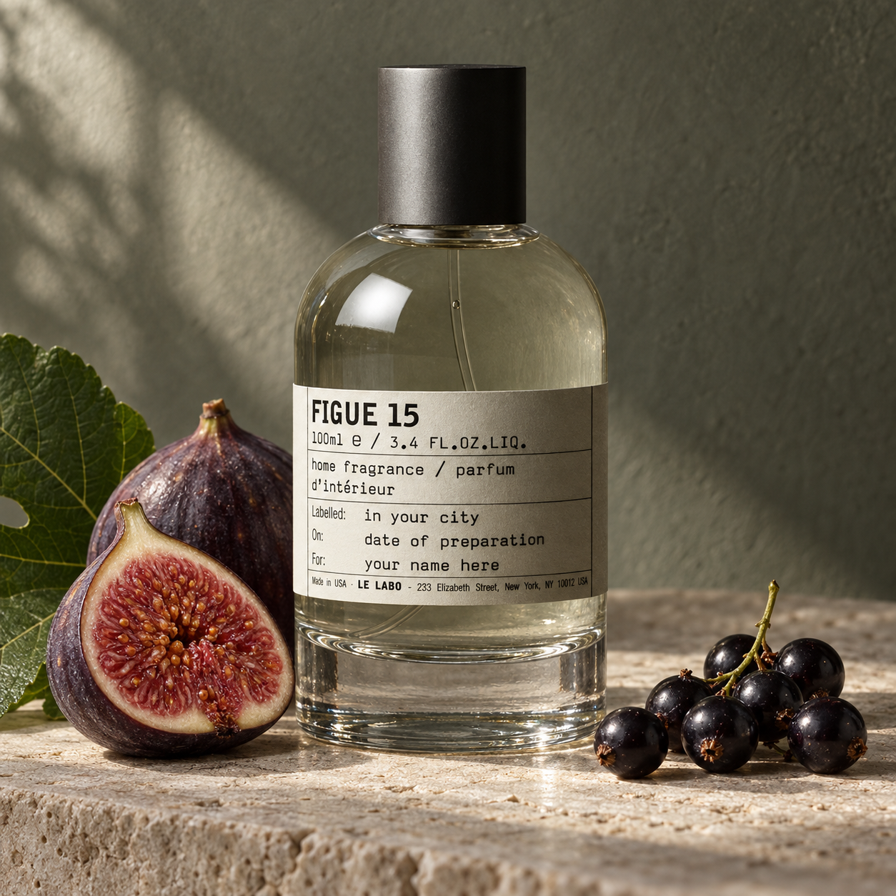 Le Labo FIGUE 15 home fragrance bottle with ripe figs, a green fig leaf, and blackcurrants on pale stone in soft natural light.
