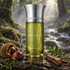 Les Liquides Imaginaires Bête Humaine beside chestnuts, lentisque leaves, and cedar wood, with a misty forest stream behind it.