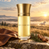 Buveur de Vent with brown leather, cypress, and cedarwood overlooking windswept grassland and a white stallion at sunrise.