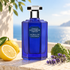 Lorenzo Villoresi Acqua di Colonia cobalt bottle beside lemon, bergamot, and lavender on a sunlit stone terrace overlooking the sea.