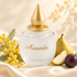 M. Micallef Ananda on ivory satin beside yellow mimosa, pear, and a purple plum in soft golden light.