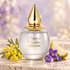 M. Micallef Ananda Nectar on ivory stone beside yellow mimosa, purple violets, and a pear wedge in soft champagne and lilac light.
