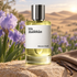 Maison Crivelli Iris Malikhân stands on sandstone beside violet irises, vanilla pods, and taupe leather, with desert dunes glowing in soft sunlight behind it.