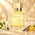 Maison Francis Kurkdjian APOM on ivory stone beside orange blossoms, lavender, and yellow ylang-ylang in soft golden light.