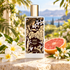 Memo Paris Jannat on sunlit stone with frangipani, orange blossoms and a grapefruit half in an airy garden setting.