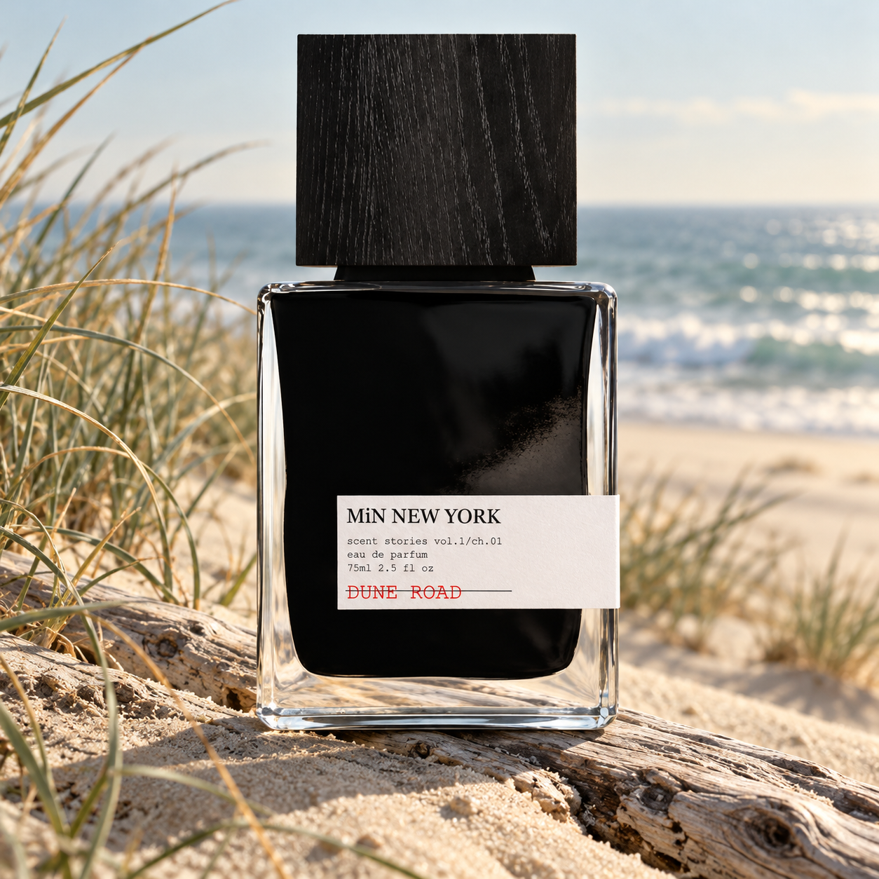 MiN New York Dune Road bottle on driftwood among dune grasses with softly blurred ocean surf in morning light.