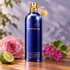 Montale Aoud Flowers beside a pink rose, magenta geranium blossoms, and bergamot on warm teak in soft daylight.