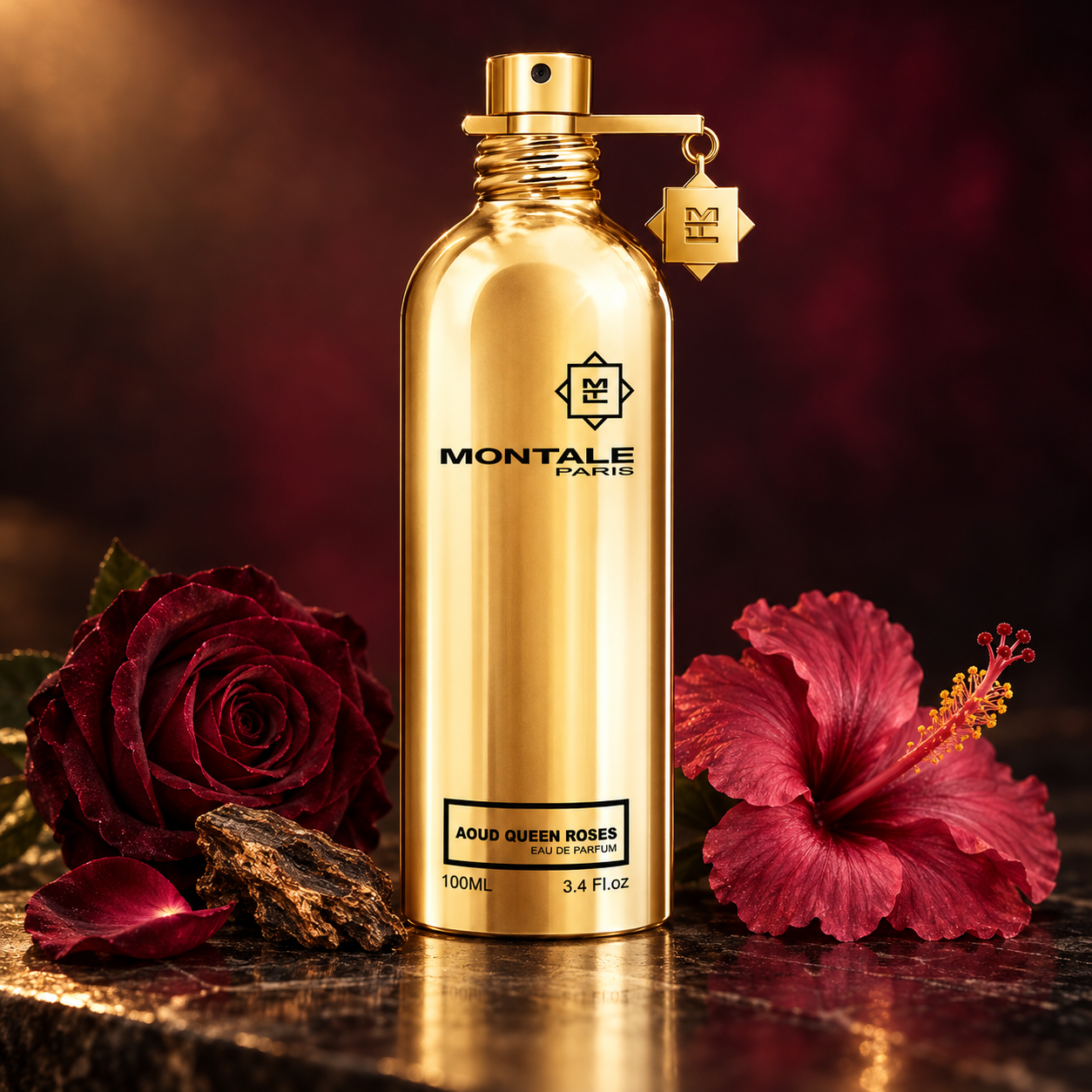 Montale Aoud Queen Roses’ gold bottle beside a burgundy rose, deep pink hibiscus, and oud wood on dark polished stone.