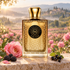 Moresque Alma Pure’s ornate golden bottle stands beside a pink May rose, blackberries, and blackcurrants, with misty rose fields in warm morning light.