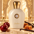 Moresque Diadema ivory bottle with whole cherries, caramel and vanilla pods on cream stone beneath a softly blurred golden arch.