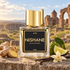 Nishane Ani on weathered stone beside ginger, bergamot, and vanilla pods with a cream orchid, overlooking softly blurred ancient church ruins in golden light.