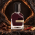 Orto Parisi Boccanera on dark stone beside chocolate, red chili, and sandalwood, framed by a shadowy rock opening with warm copper light.