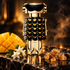 Paco Rabanne Fame Parfum black-and-gold bottle with mango, jasmine and resin on dark polished stone.